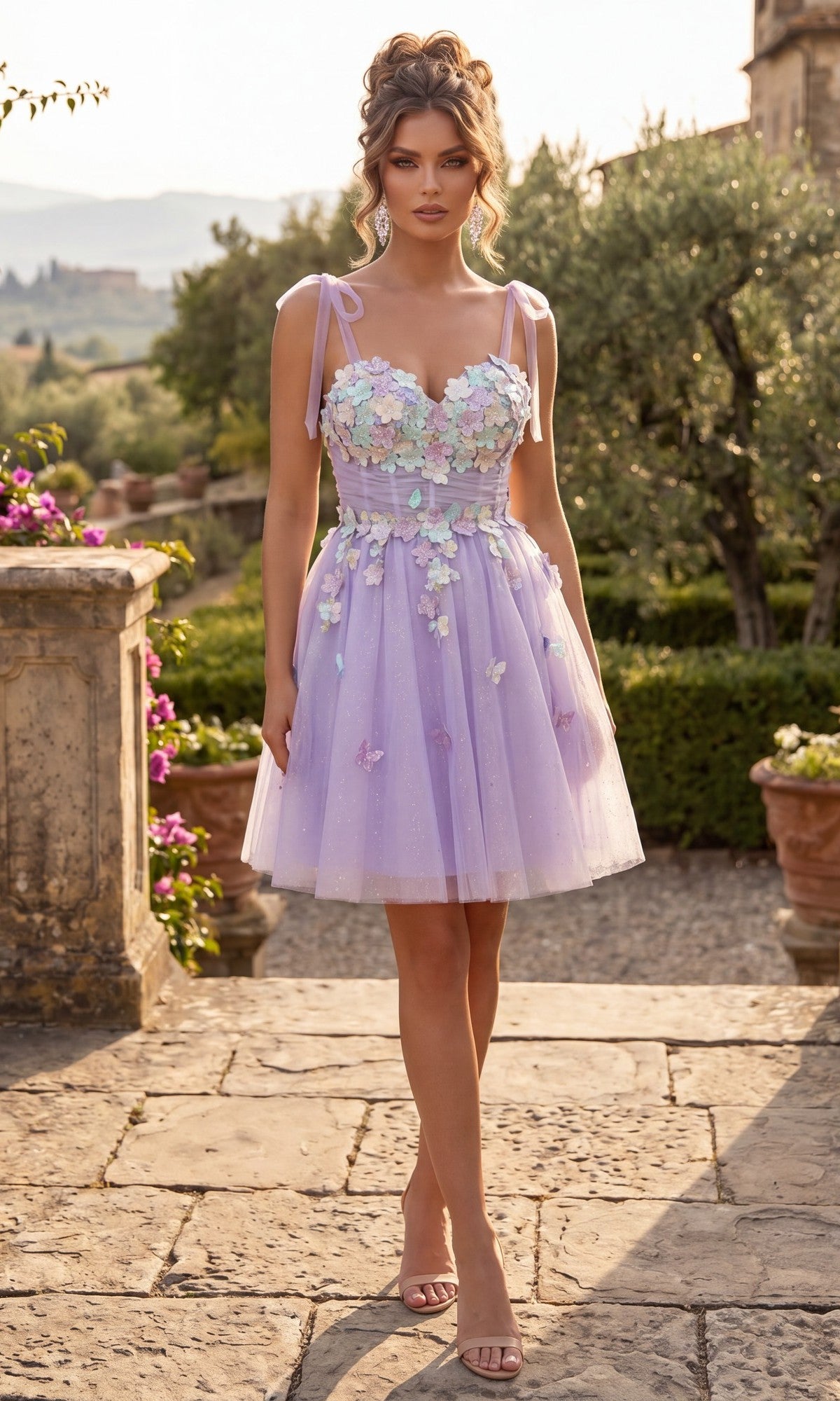 A woman stands outdoors on a stone pathway surrounded by greenery and potted plants, wearing the Chicas C354 Short Homecoming Dress in lilac, featuring an a-line tulle short skirt and delicate 3D floral appliques.